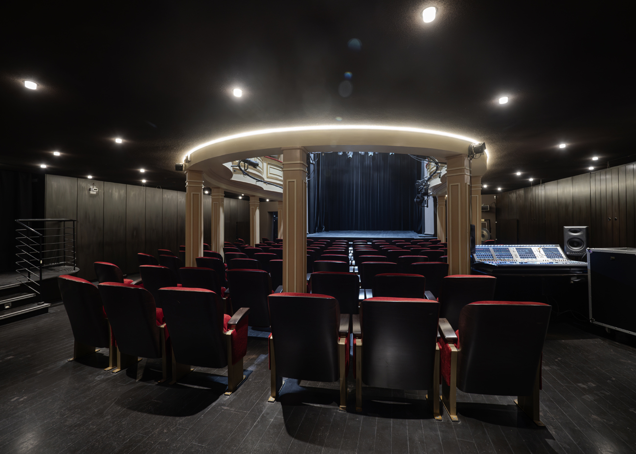 Zdjęcie parteru na sali widowiskowej Teatru Starego. Ujęcie zza dziewięciu rzędów foteli. Pomiędzy fotelami znajdują się jasne kolumny podtrzymujące loże. Jedna z kolumn jest na środku ósmego rzędu. Po bokach w równych odstępach są po trzy kolumny po obu stronach. W głębi ujęcia scena. Po lewej stronie jest podest ze schodkami do wyjścia ewakuacyjnego, po prawej konsola dźwiękowca.